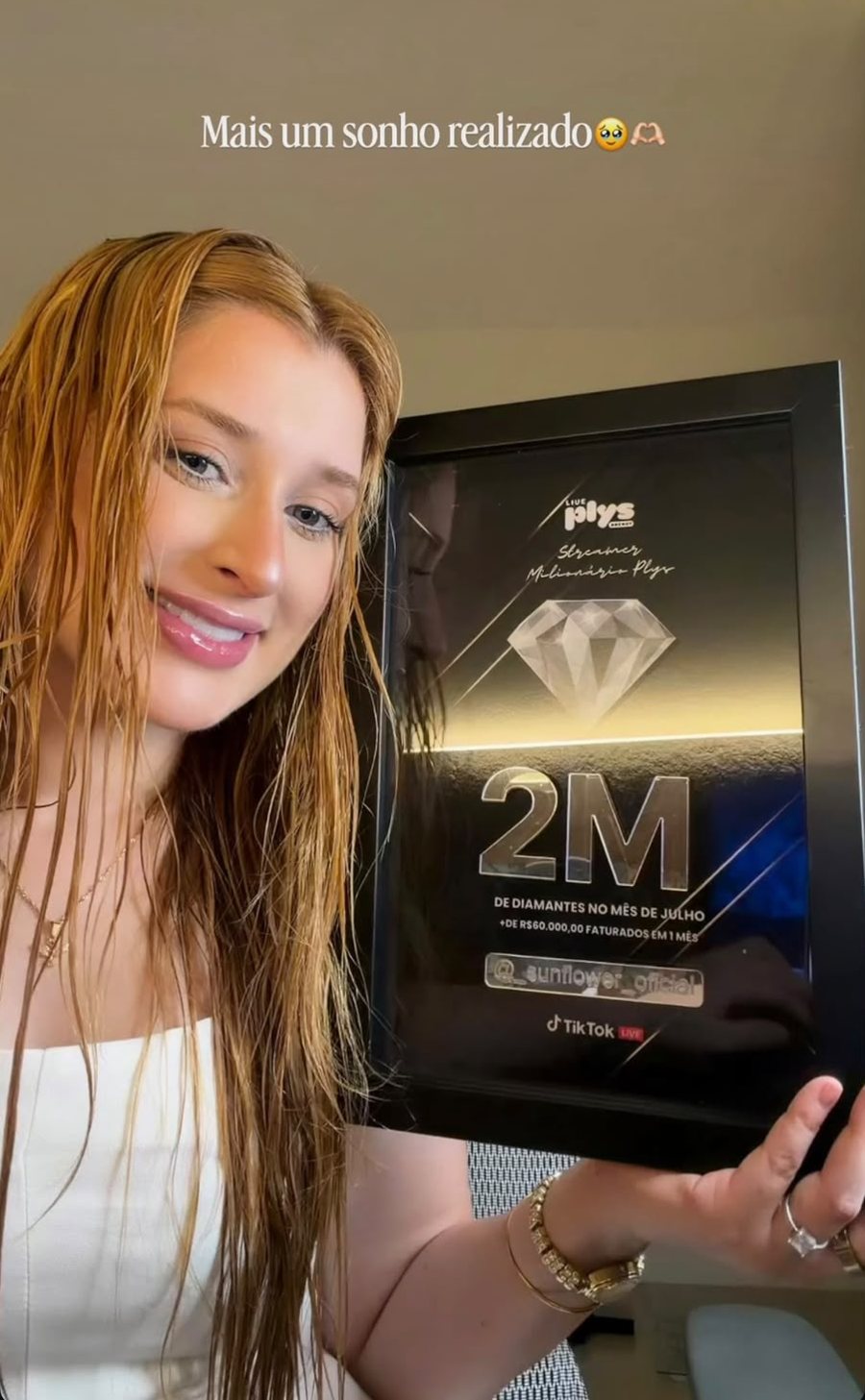 Host segurando a placa de 2 milhões de diamantes no mês de julho